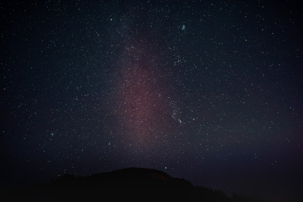 the night sky with stars above a mountain