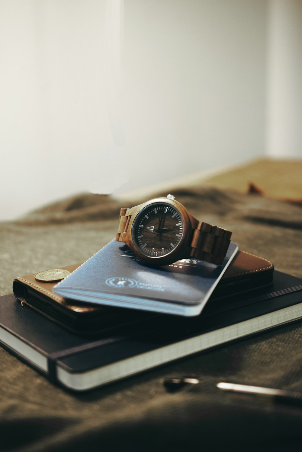 a wallet, watch and passport on a bed