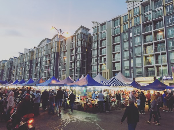 A bustling market street in Tulkarem with students engaging with local merchants under green and blue banners.