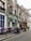 A charming Parisian street café with vintage appeal features purple tables and chairs aligned outside. Climbing vines decorate the building's exterior, and colorful flowers add a welcoming touch.