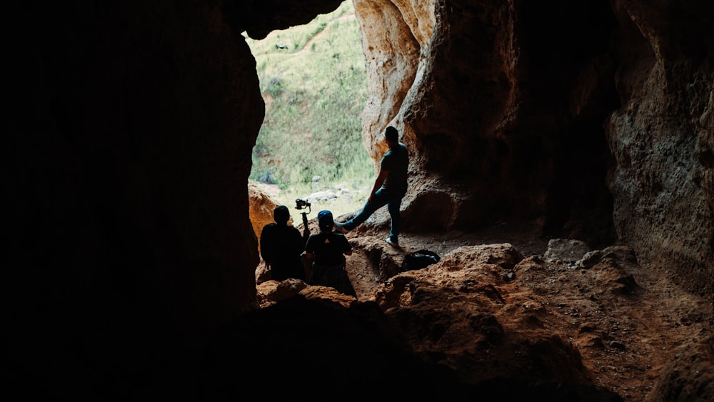 three person sitting on cave