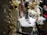 A mannequin is adorned with jewelry, including a necklace and brooch, set against a festive holiday backdrop. The scene is decorated with golden baubles, white garlands, and wrapped gifts with white bows, creating a luxurious and celebratory atmosphere.