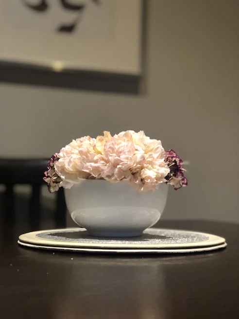 Lavender-hued 3D printed decorative bowl holding fresh flowers on a minimalist wooden table