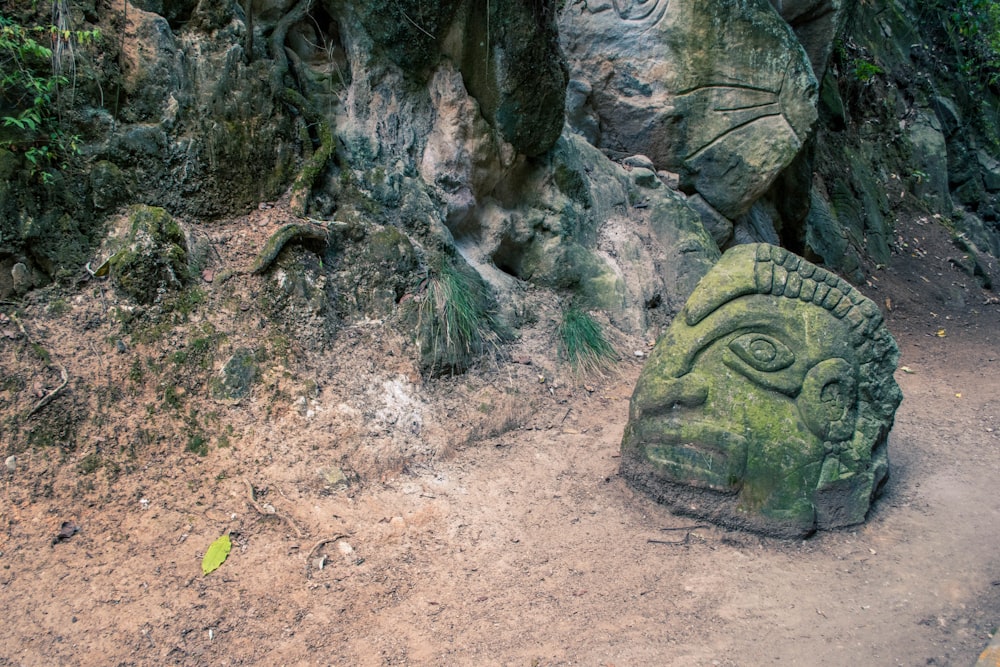 green concrete head statue on pathway