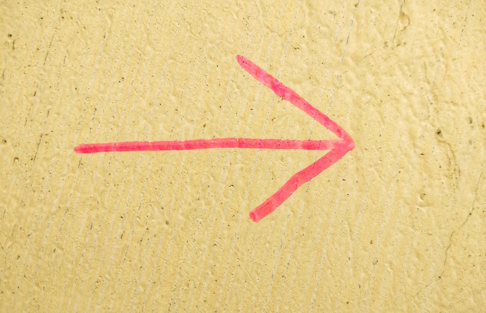 uma seta vermelha desenhada em uma superfície amarela