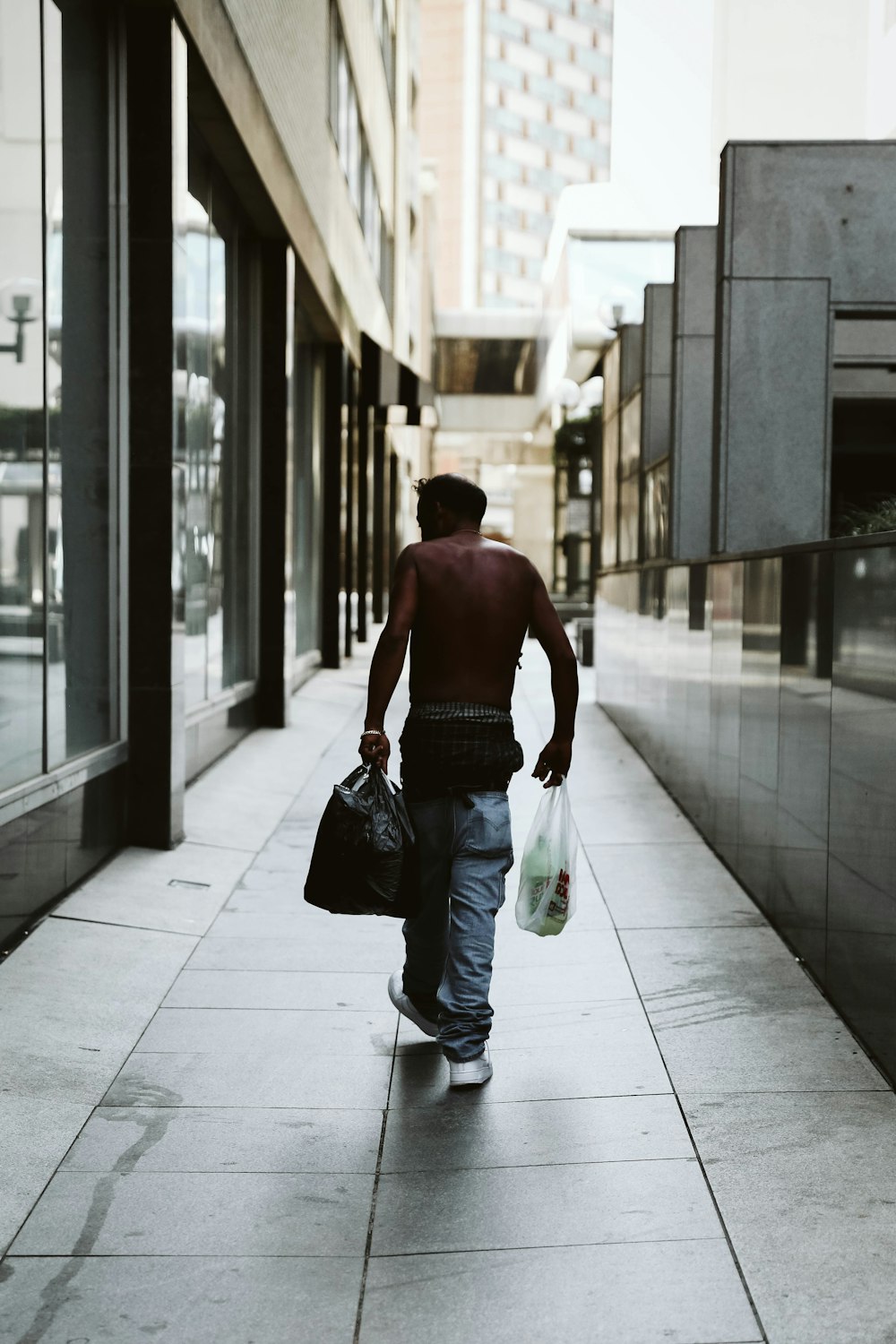 person in blue denim pants holding plastic bags