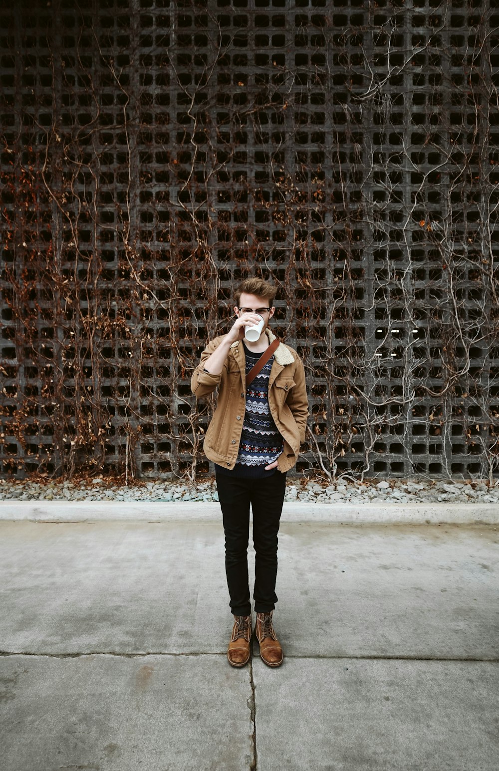 man wearing brown jacket holding cup while drinking