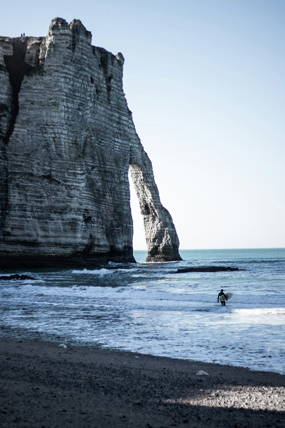 man walking in sea beside island with hole