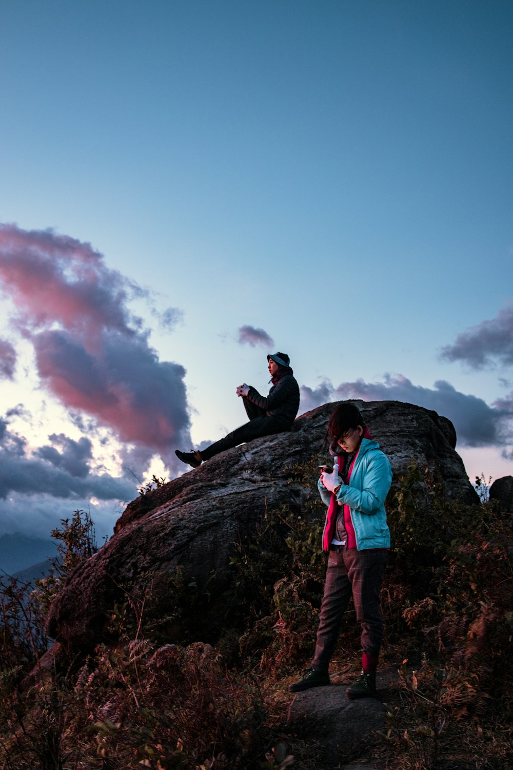 duas pessoas sentadas e em pé sob um céu azul calmo durante o dia