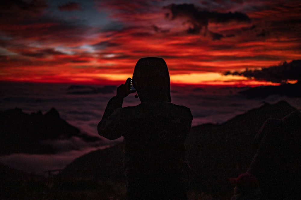 silhouette photography of person looking at the sea during golden hour