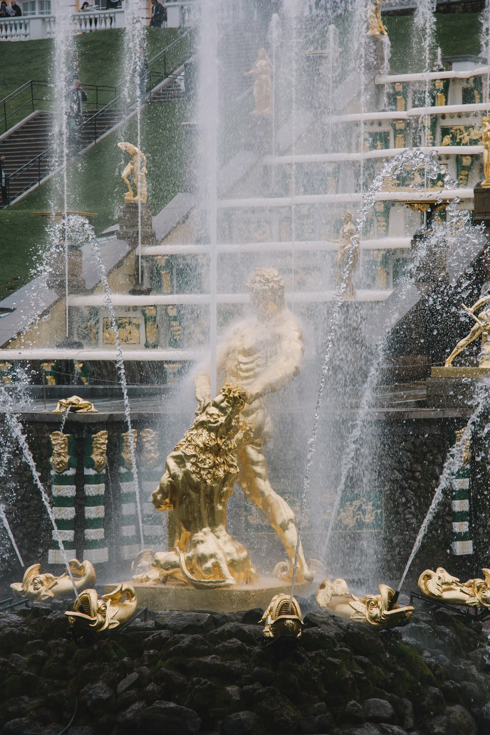 brass-colored statues on black and white water fountain during day