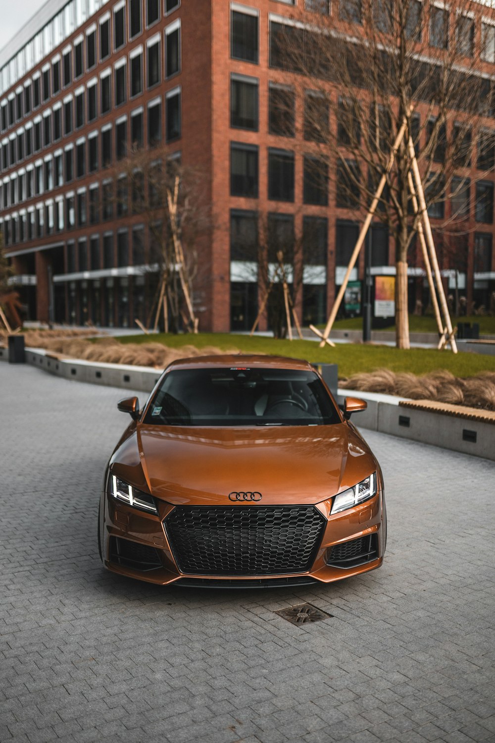 Une voiture de sport orange garée devant un immeuble