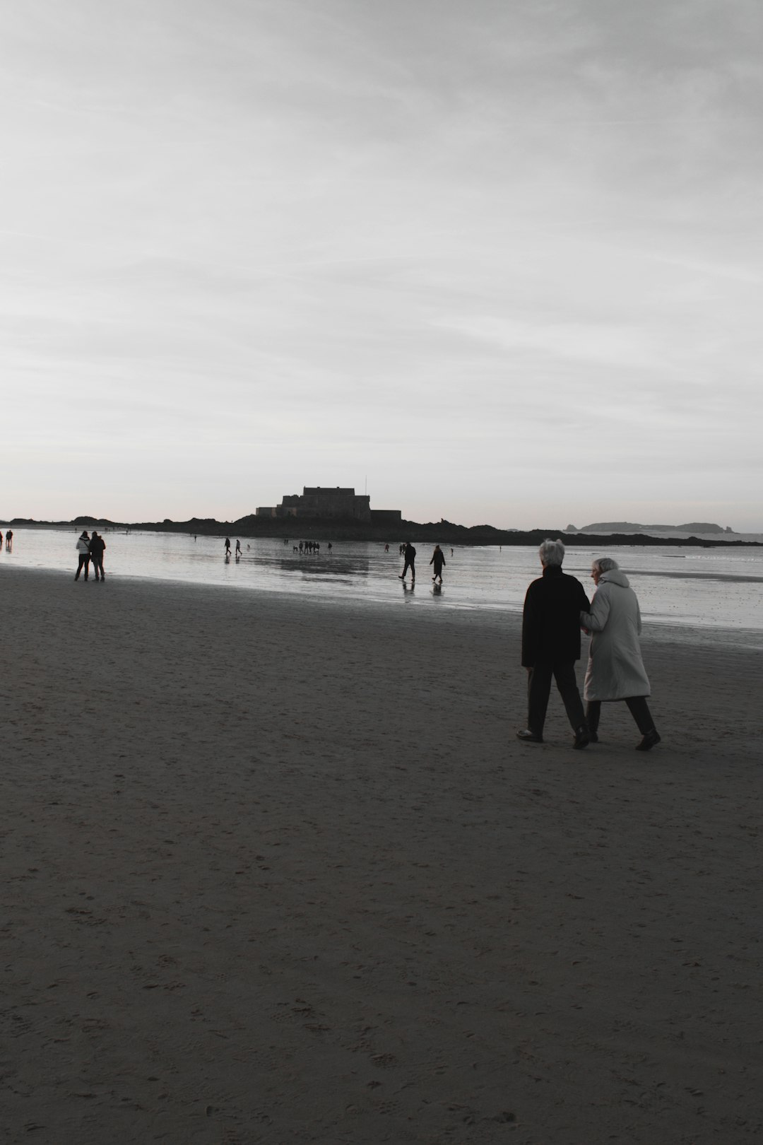 grayscale photo of people on seashore during daytime