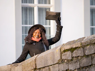 A smiling woman outdoors, showing off her stylish Manoviva gloves on a crisp day.