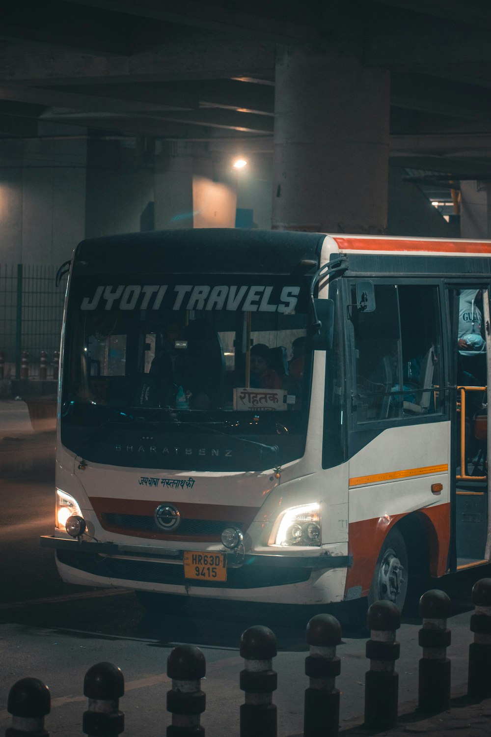 白、赤、黒のJyoti Travelsバスが通りを通り過ぎる