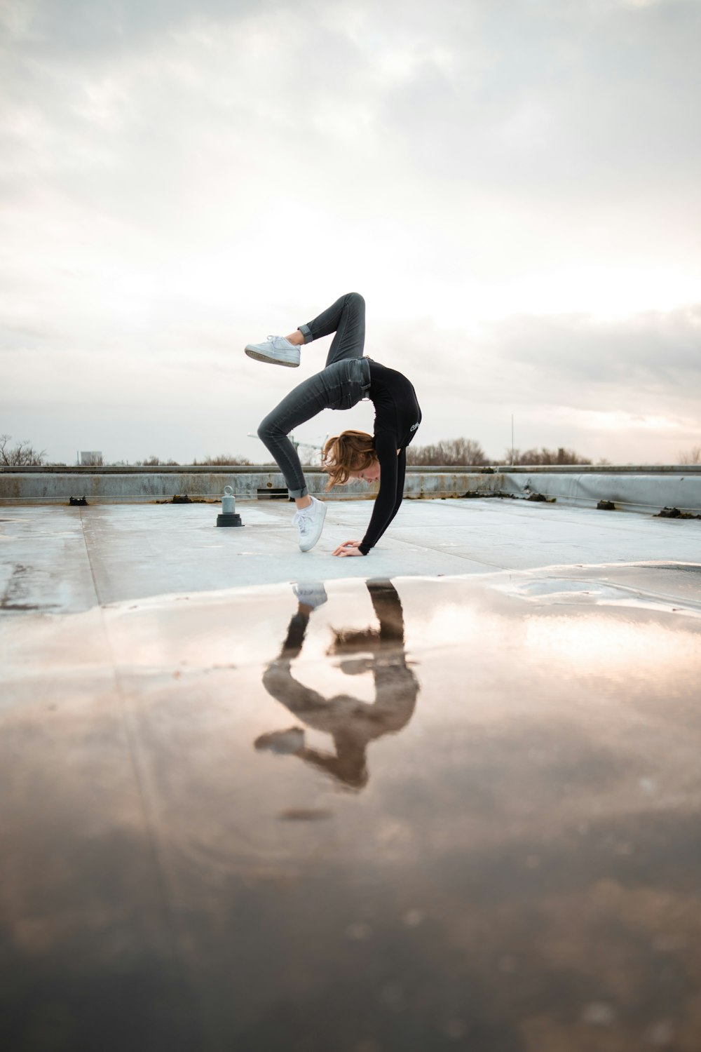 woman doing bridge posts reflecting on water puddle