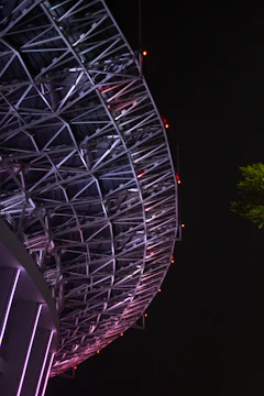 Steel structure framework rising against a dark sky with green fluo accents.