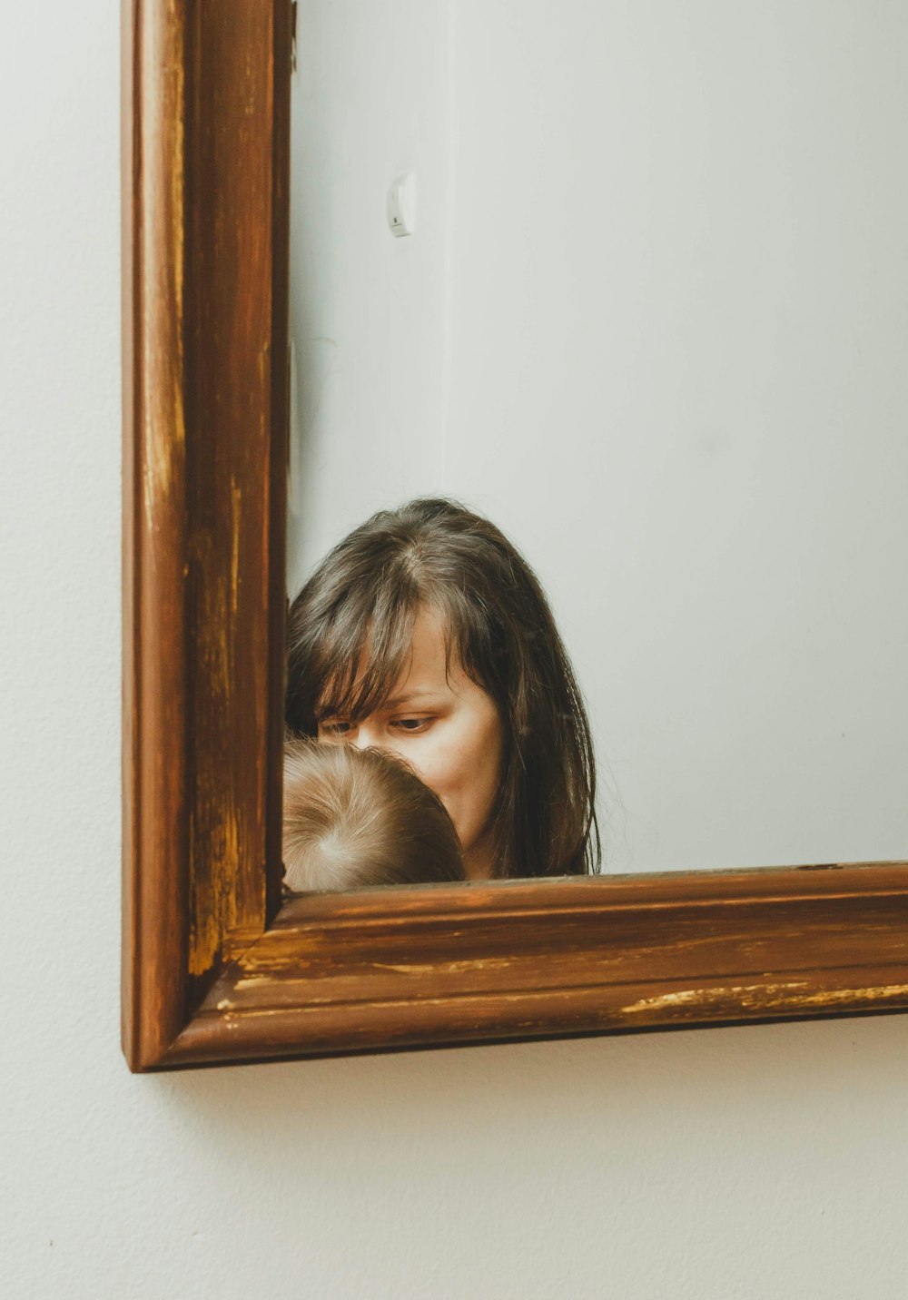 a woman holding a baby in front of a mirror