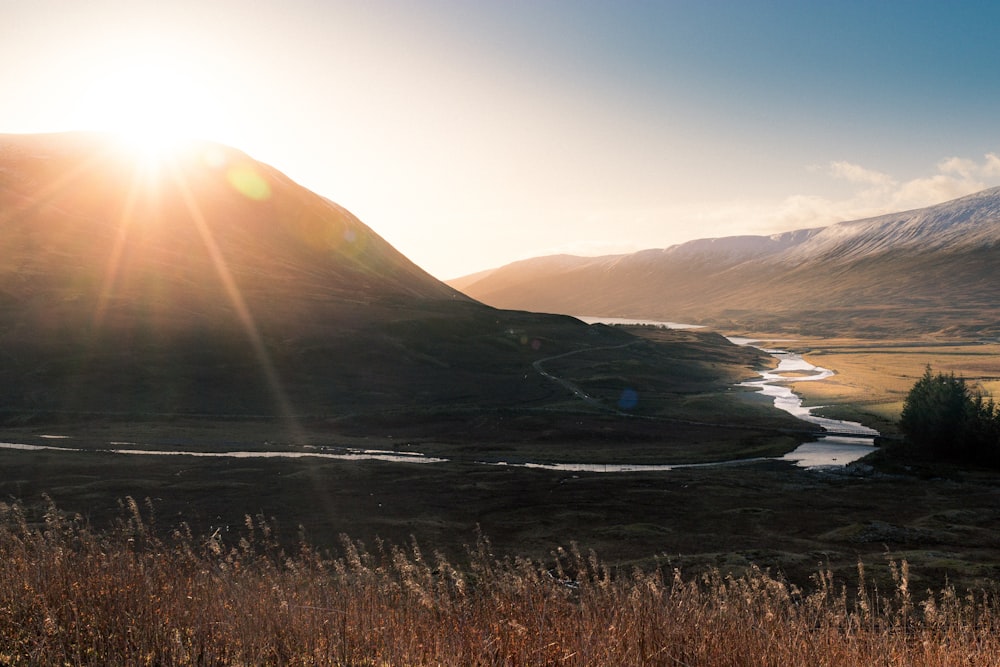 river, field, and mountains during day