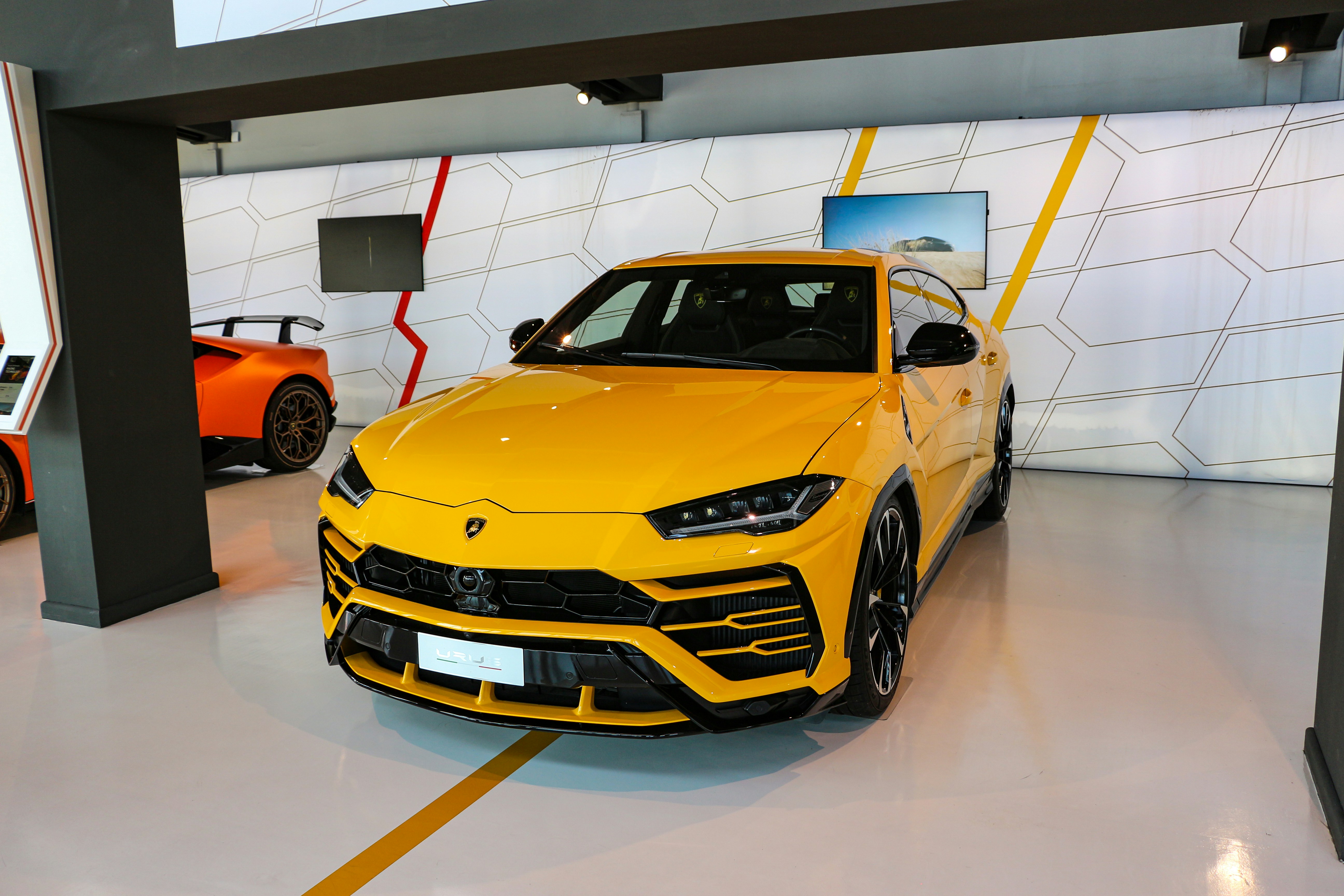 Black Lamborghini Urus SUV in modern showroom, dark polished floor, moody ambient lighting