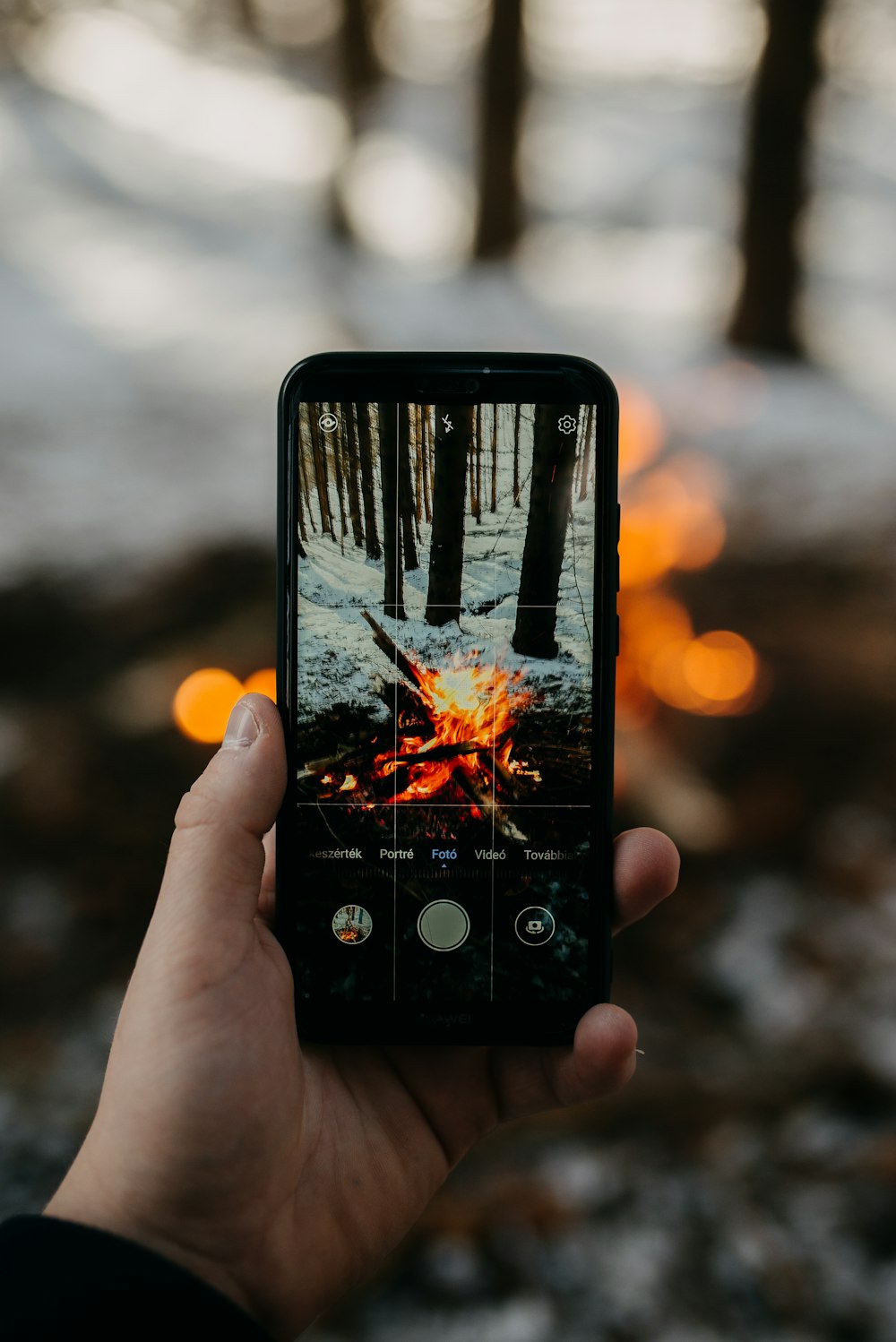 selective focus photography of person taking photo of burning firewood