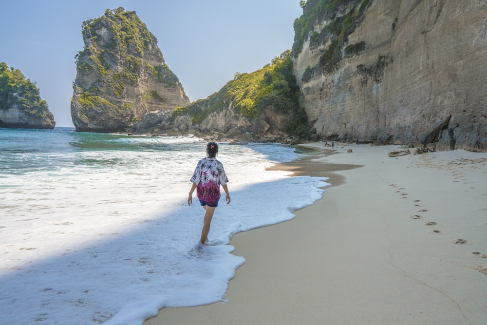 donna che cammina in riva al mare durante il giorno