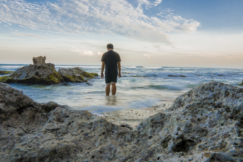 man standing on seashore near rocks