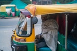 man sitting inside yellow and green autorickshaw