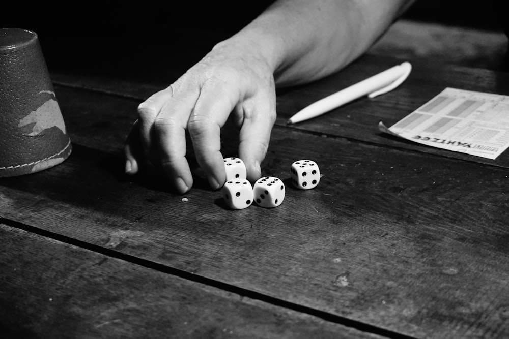grayscale photography of person playing with dice