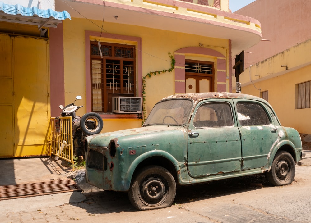 Parcheggio coupé verde vintage abbandonato vicino alla casa dipinta di giallo