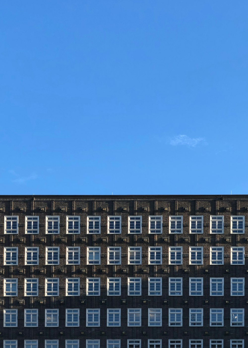 Edificio de gran altura marrón y blanco bajo cielo azul y blanco