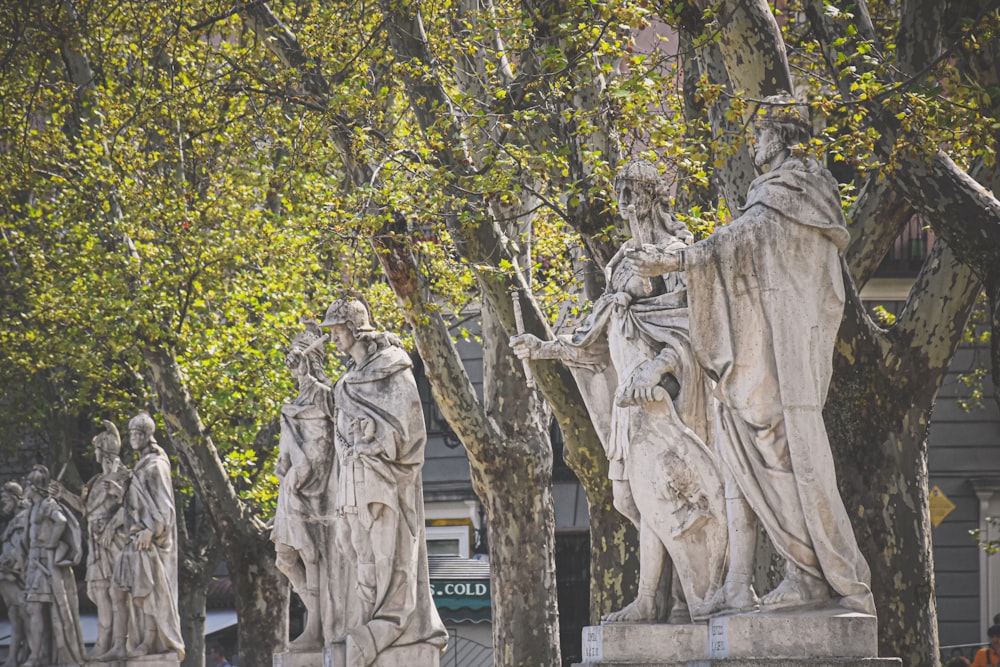 human statues beside trees during day