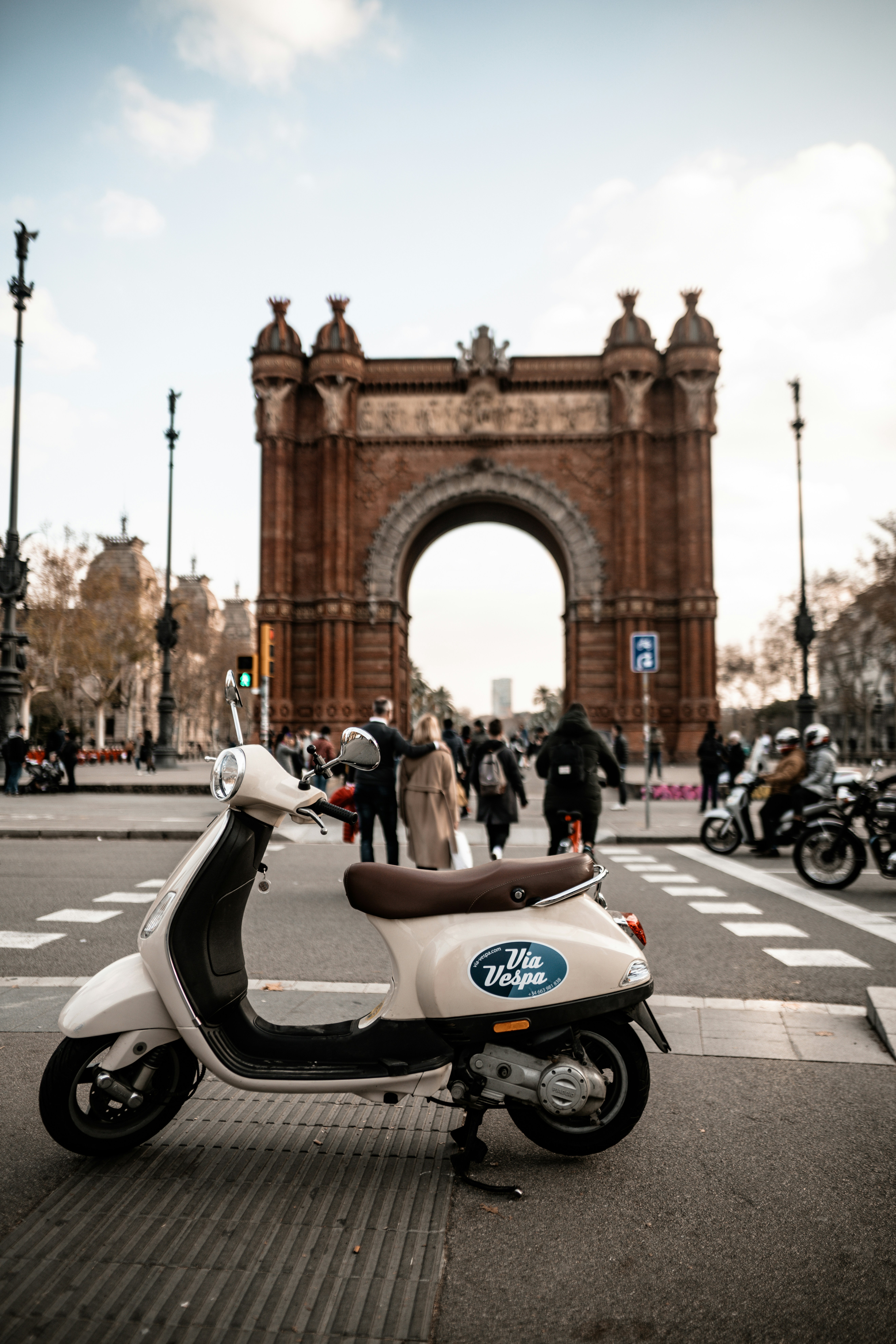 selective focus photography of parked white motor scooter near brown arch