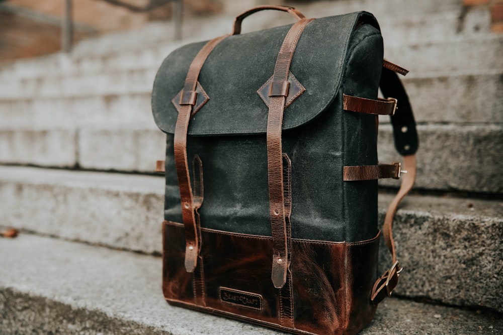 brown and black leather bucket backpack on concrete staircase