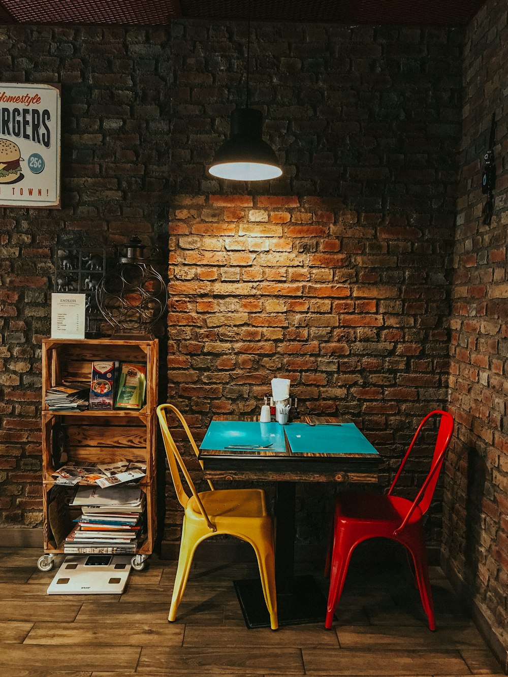 square blue wooden table beside brown brick wall