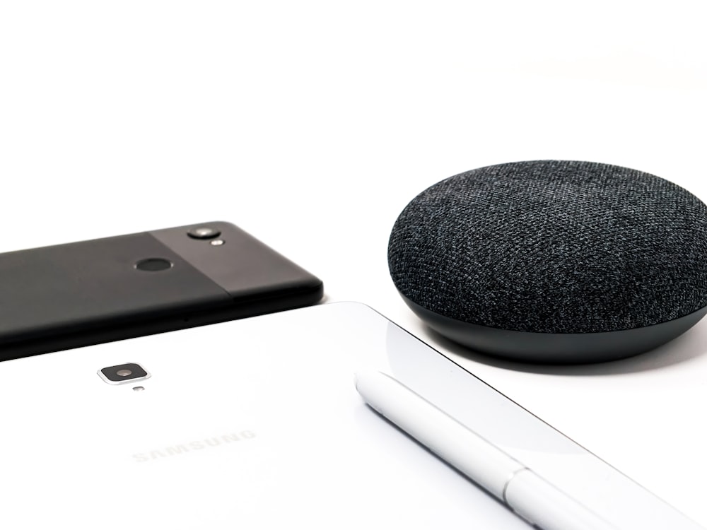 round black portable wireless speaker and black smartphone in white background