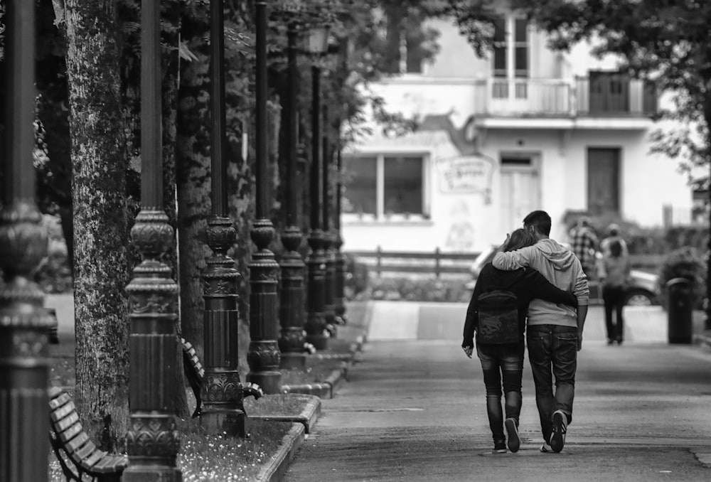 grayscale photo of two person hugging each other