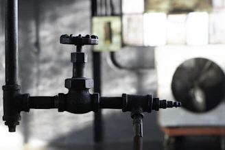 Close-up of an industrial valve with gauges and pipes in a dark, technical setting.