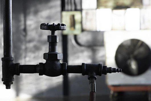 Close-up of a high-quality industrial valve with a backdrop of an oil refinery at sunset.