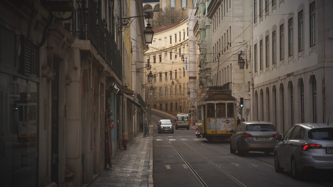 vehicles and train on road near buildings during day