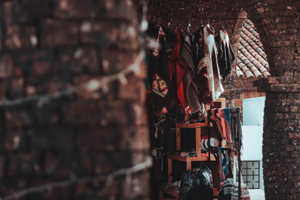 a room filled with lots of clothes and a brick wall