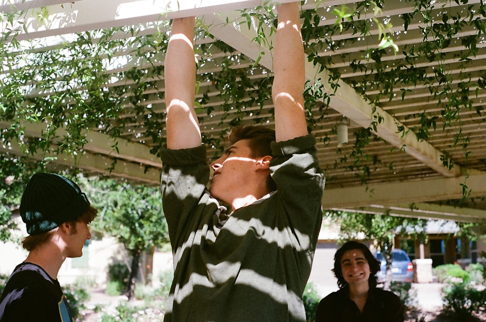 man hanging from a pergola