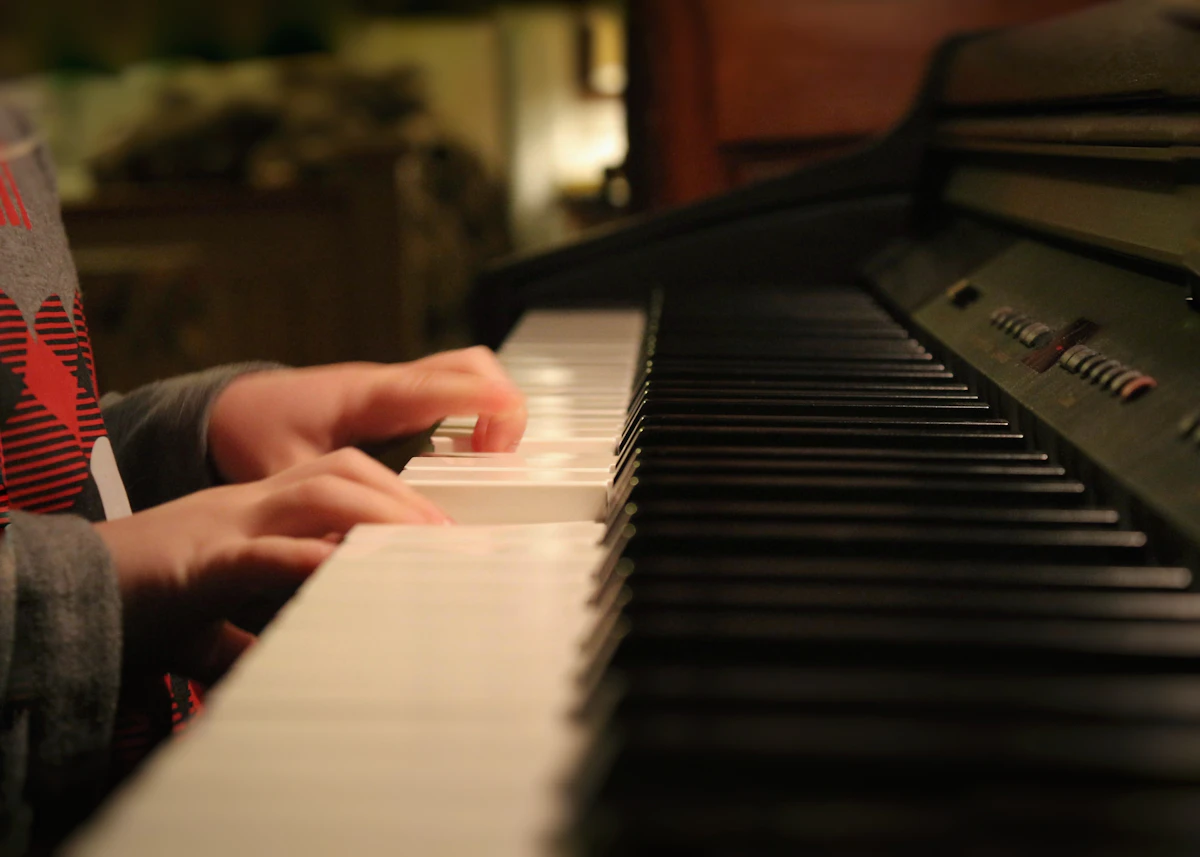 A child's hands playing the keys of a piano