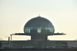 A futuristic transparent dome covering a cityscape under a cloudy sky.
