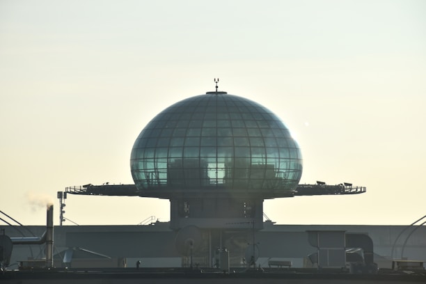 A futuristic transparent dome covering a cityscape under a cloudy sky.
