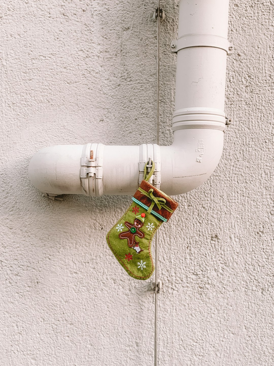 green Christmas stocking hanging on white pipe