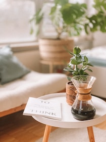 A minimalist wooden coffee table with clean lines, styled with a soft beige throw and a small plant.