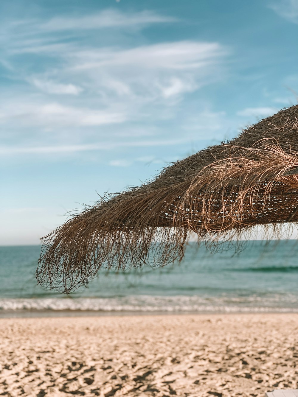thatch parasol on sand seashore during day