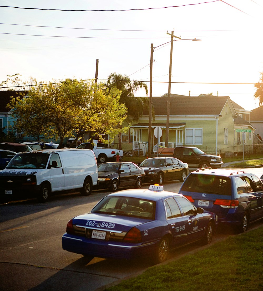 assorted cars parked at the side of the road near houses during day