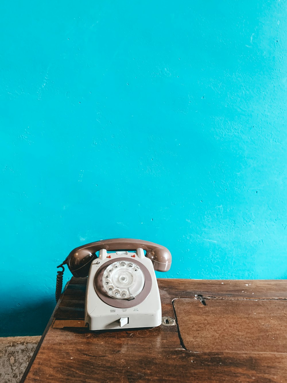 white and gray rotary phone on brown surface